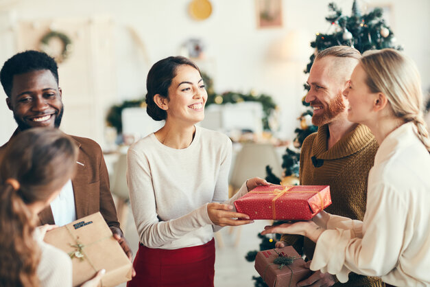 Five people exchanging gifts at a holiday party 