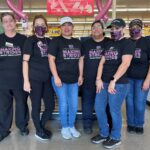 People in front of a Food Town grocery store sign wearing Making Strides Against Breast Cancer T-shirts