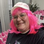 Woman with p ink hair and ball cap gathering Making Strides Against Breast Cancer items