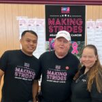 People in matching T-shirts in front of a Making Strides Against Breast Cancer sign