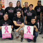 People inside a grocery store wearing matching T-shirts and holding Making Strides Against Breast Cancer signs