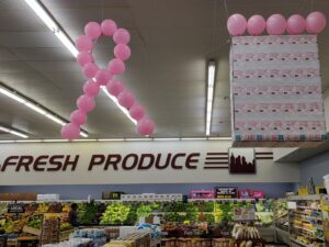 Grocery produce section decorated with pink balloons and Making Strides Against Breast Cancer donation cards