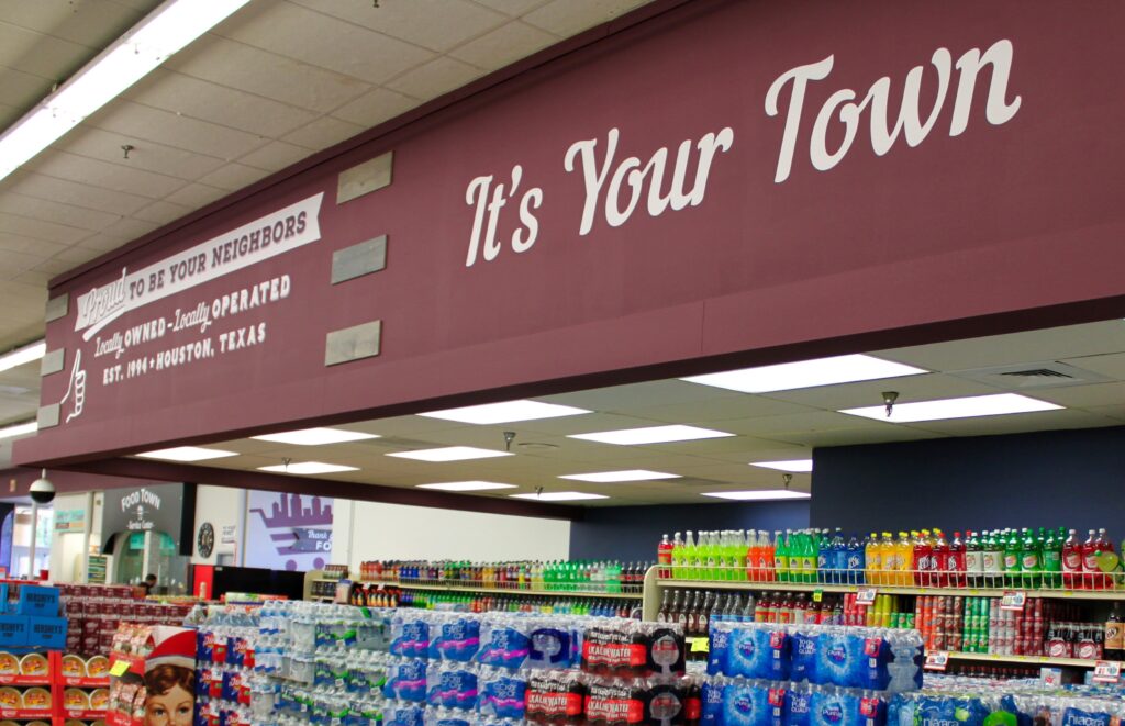 Grocery store beverage section with signage reading “It’s Your Town”