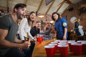 People playing with cups and ping pong balls at a holiday party