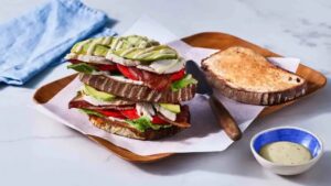 Sandwich made with Thanksgiving leftovers topped with avocado and served with sauce on the side