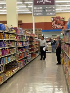 Two men evaluating the shelves inside supermarket
