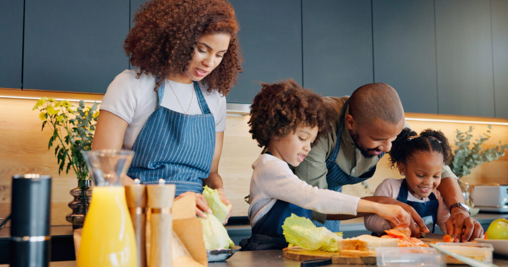 Woman, man and children in aprons preparing a family meal
